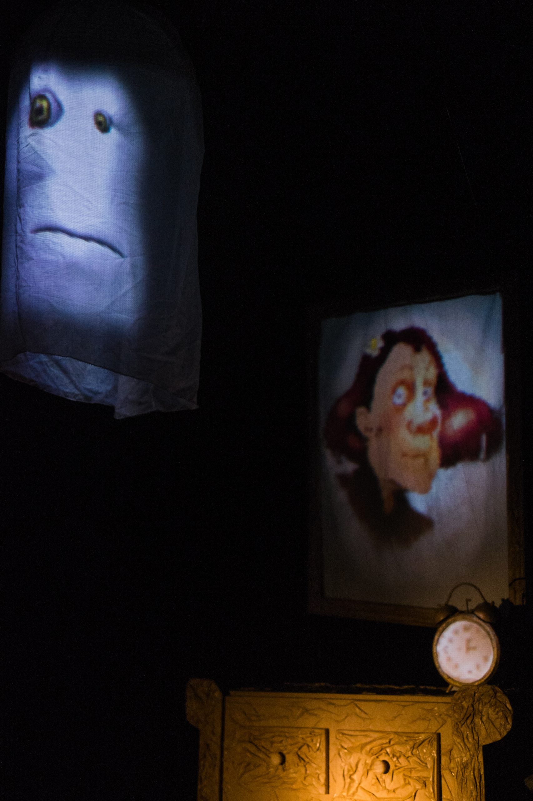 Des visages, un portrait et une horloge dans la chambre nocturne.