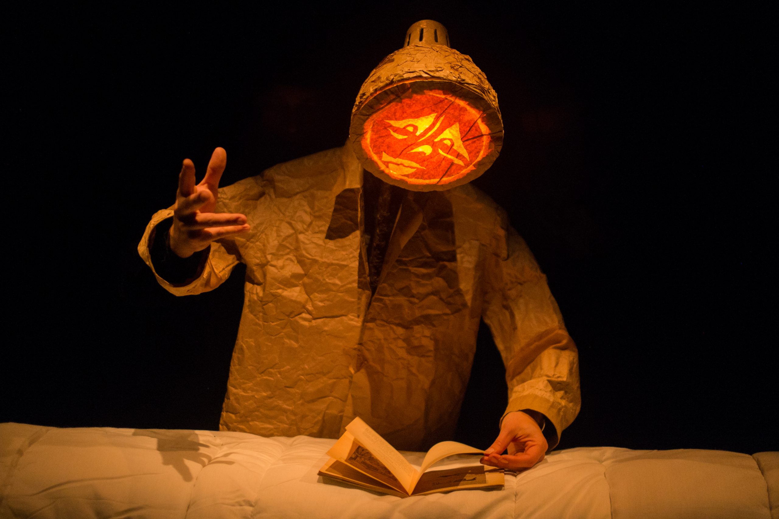 Un personnage de papier au visage lumineux lit un livre.